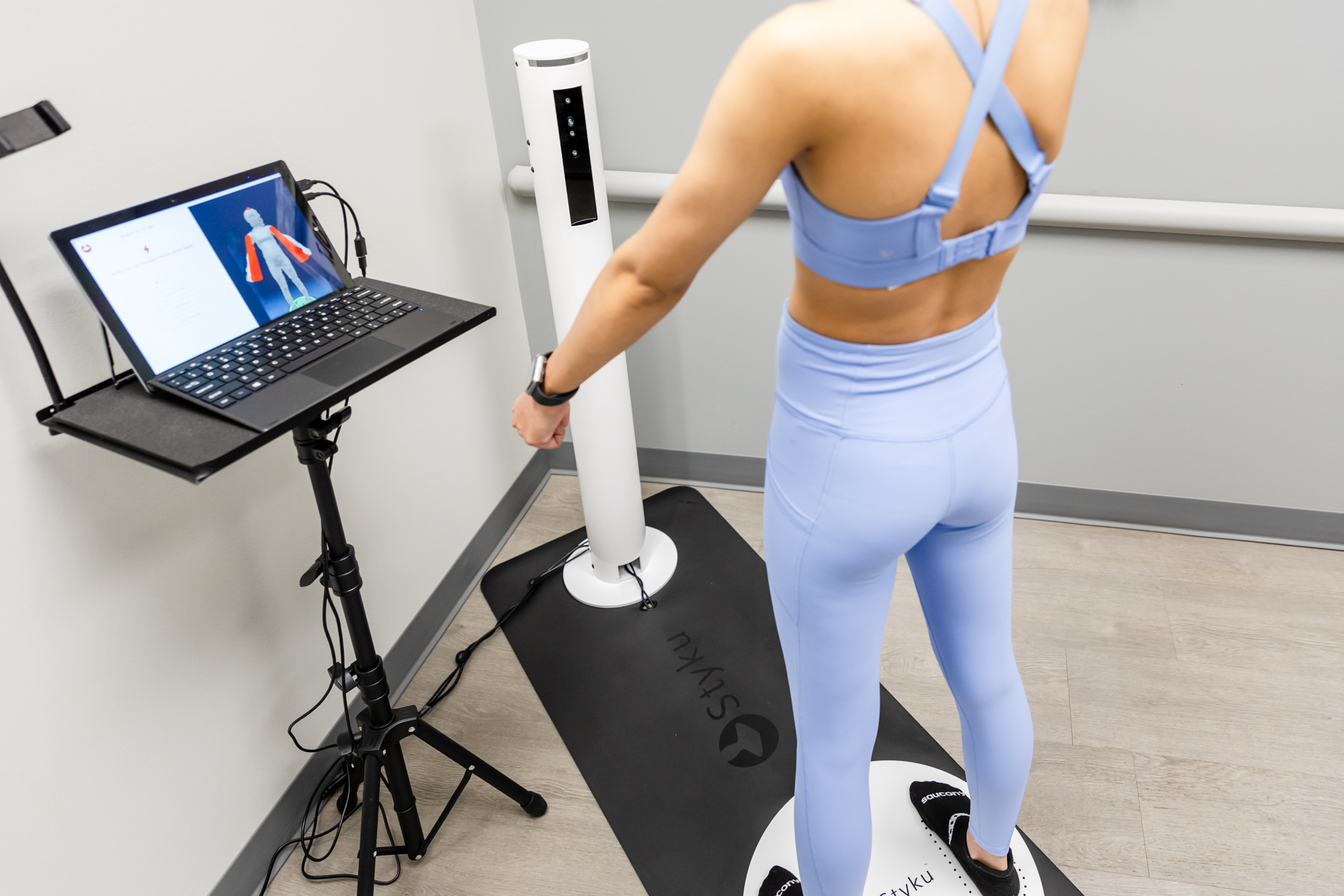 The lower half of a woman standing on a body scanner with a laptop showing her insights to support her progress with Healthtec's weight loss program in Abilene.