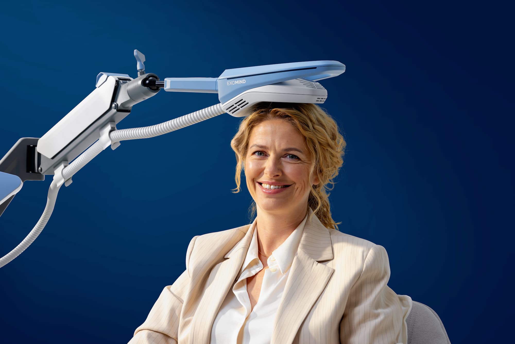 A woman sitting in front of a blue background with an Exomind, in Abilene, applicator on her head.