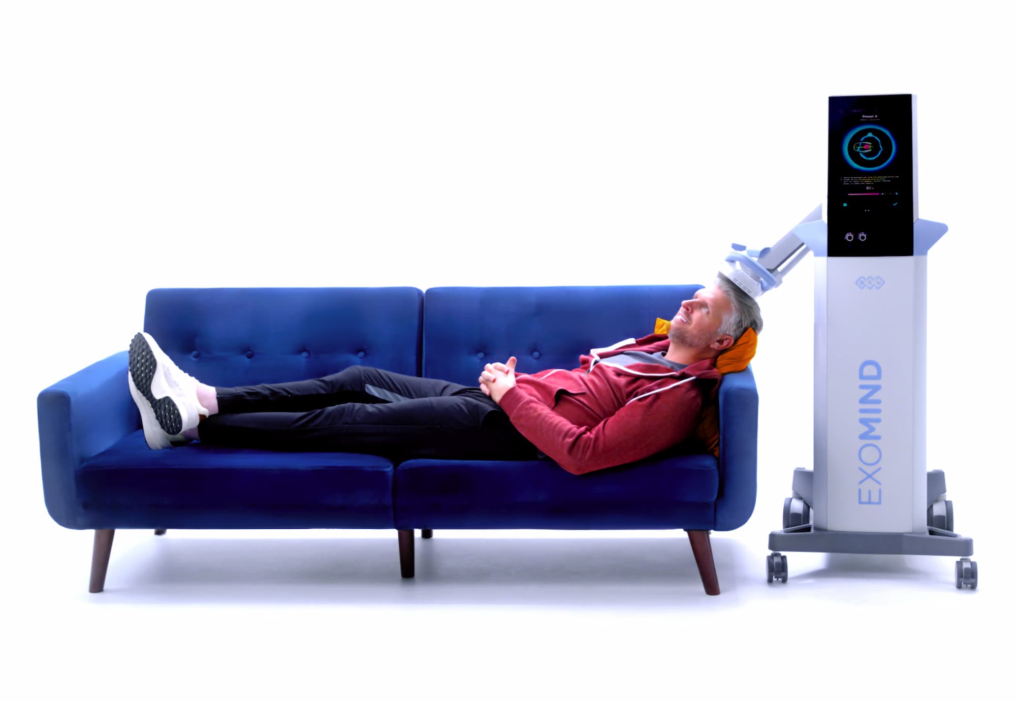 A man lying on a blue couch with the Exomind (best treatment for anxiety in Abilene) device applied to his head.