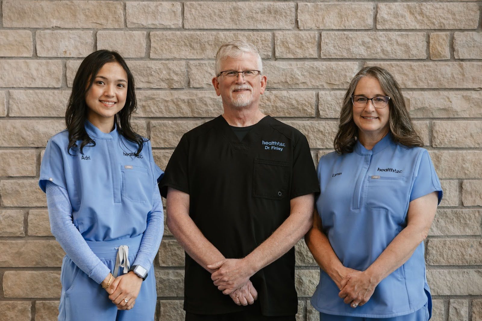 The medical providers at Healthtec standing against the brick wall of their practice where they administer a weight loss program in Abilene.
